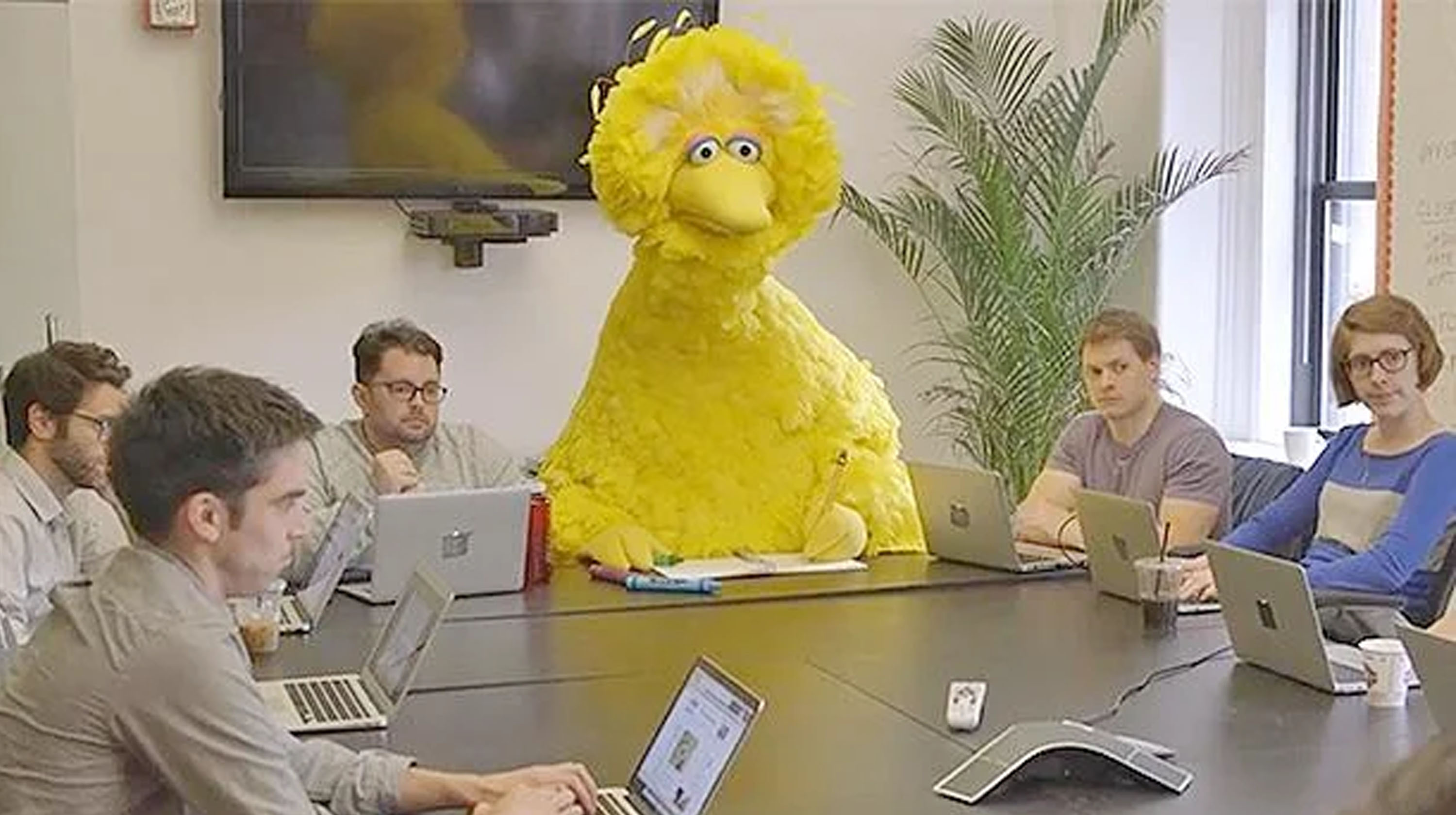Big Bird in a meeting, looking out of place among the humans.