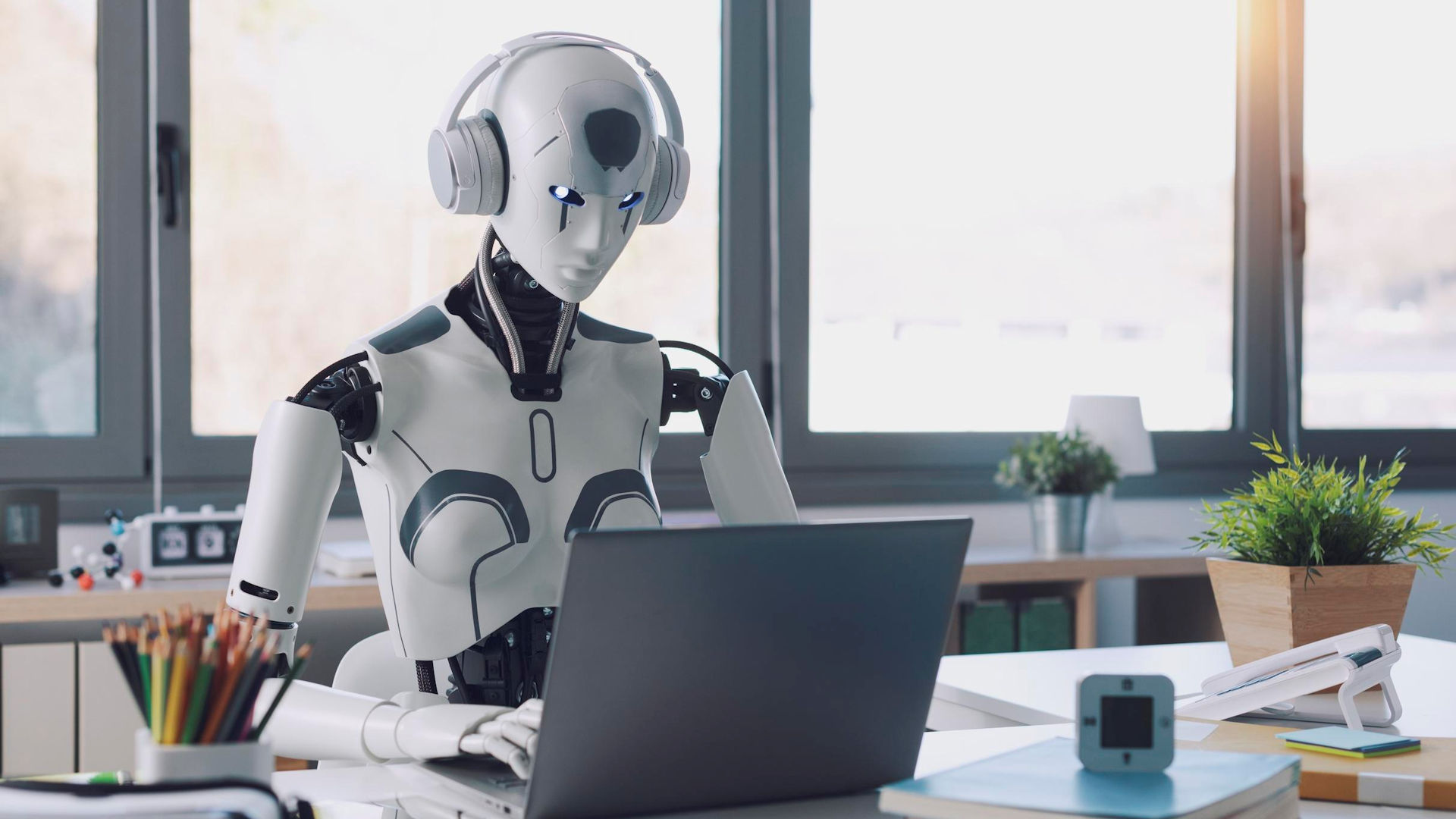 A humanoid robot working on a laptop.